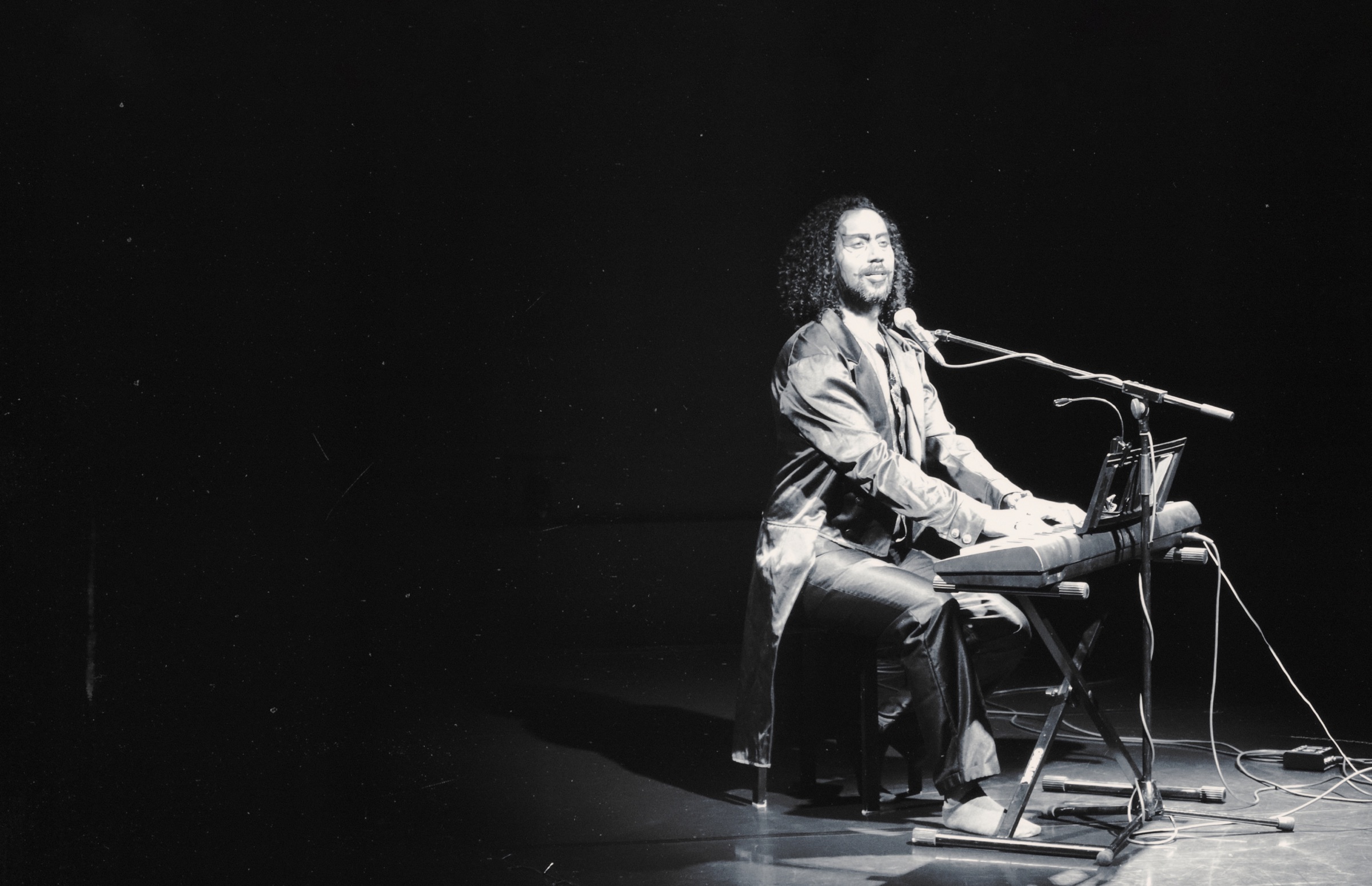 Juan Zuleta performing at the keyboard, lit on a dark stage