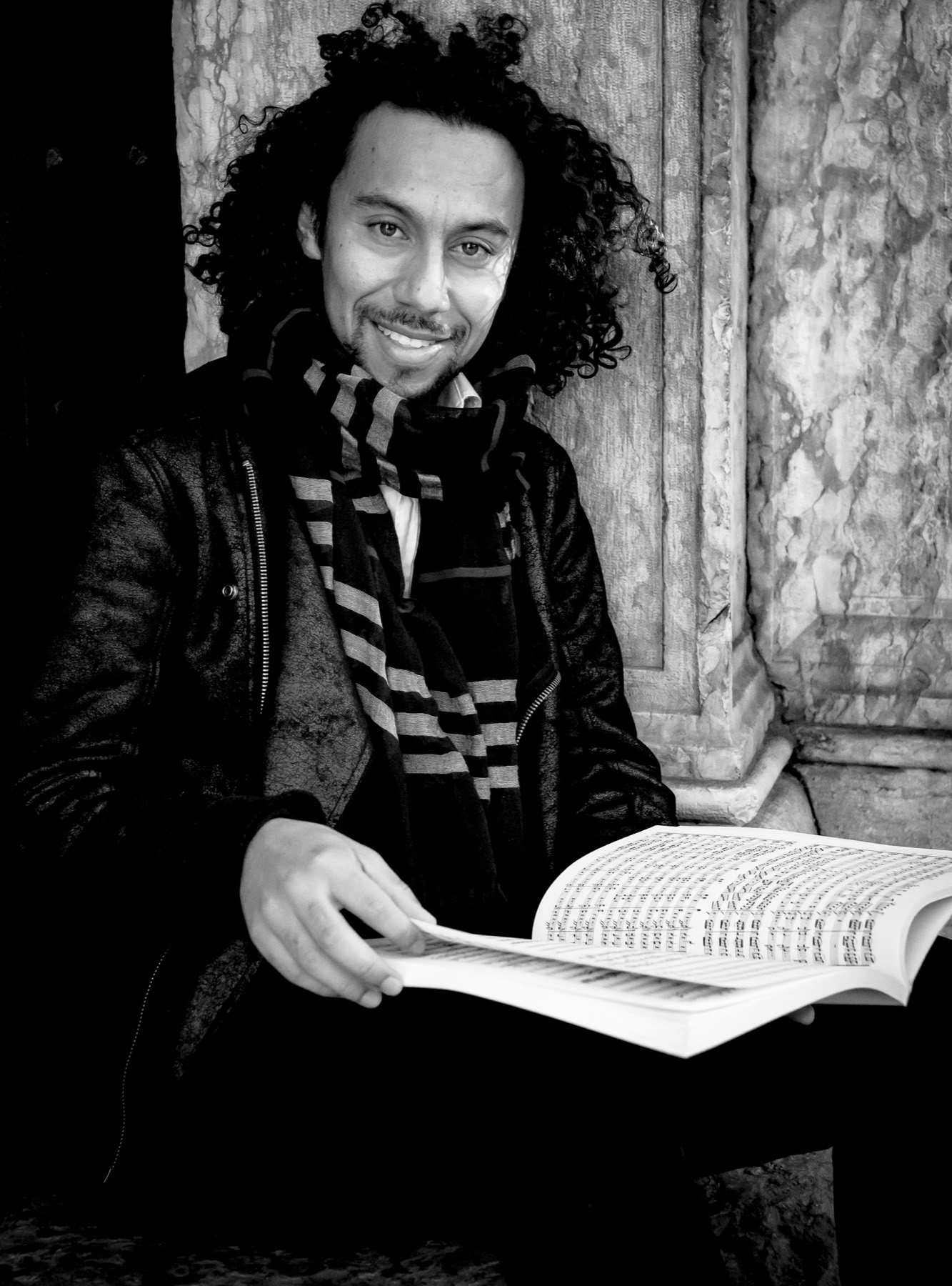 Juan Zuleta reading from a bound score, smiling